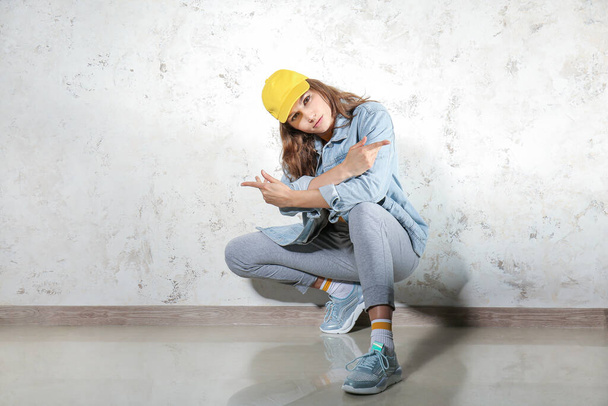 Beautiful female hip-hop dancer against light wall - Zdjęcie, obraz