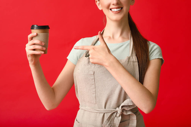Jonge vrouwelijke barista op kleur achtergrond - Foto, afbeelding