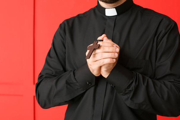 Молодой священник молится Богу на цветном фоне, крупным планом
 - Фото, изображение