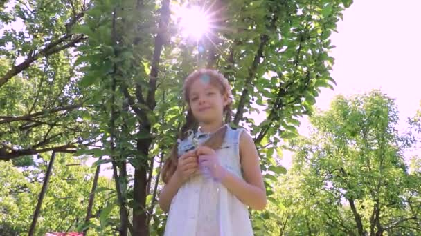 beautiful girl in a summer garden, children's holidays. little cute girl in a green garden. child's portrait - Filmagem, Vídeo