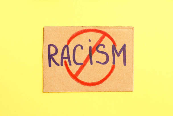 Placard with crossed out word RACISM on color background - Foto, imagen