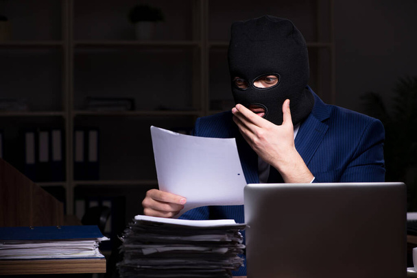Mężczyzna pracownik kradzież informacji w biurze czasu nocnego - Zdjęcie, obraz