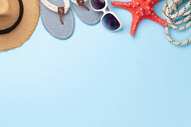 Summer vacation items and accessories. Flip flops, sunglasses and sun hat on blue background. Top view flat lay with copy space - Photo, Image