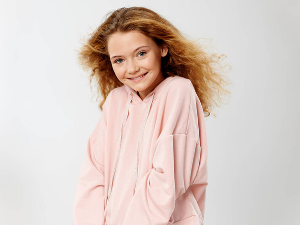 Glückliches Mädchen im rosa Pullover lächelt in die Kamera  - Foto, Bild