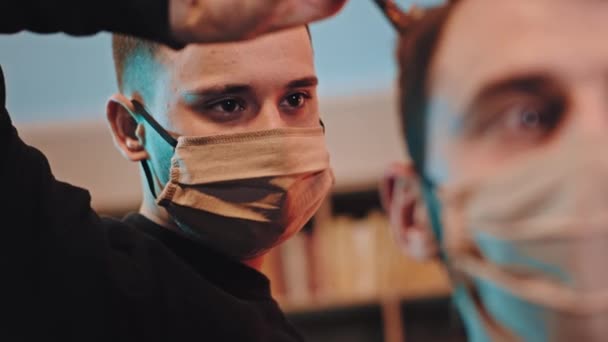 Pandemic of Coronavirus 2019 profesionální kadeřník detailní záběr do kamery s ochrannou maskou dělat účes na klienta, stejně jako s ochrannou maskou - Záběry, video