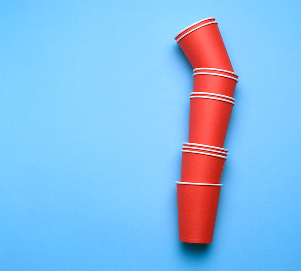 egy halom piros papír eldobható csésze kék háttér, lapos laikus, koncepció környezetbarát, nulla hulladék  - Fotó, kép
