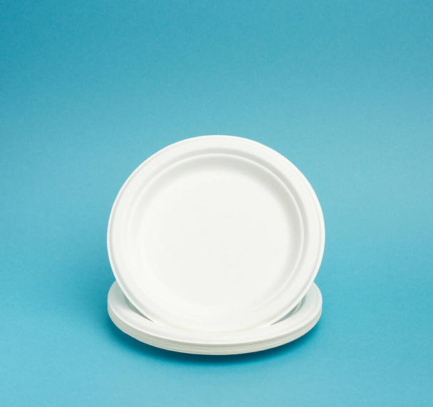 стопка одноразовых белых бумажных тарелок на бежево-голубом фоне. Концепция отказа от пластика, охраны окружающей среды
 - Фото, изображение