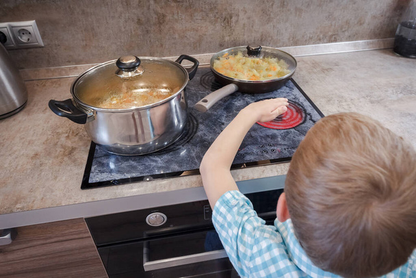 Kid risking accident with cooker in kitchen. Hazard at home. Concept of burn children. Warning burning human skin - Φωτογραφία, εικόνα