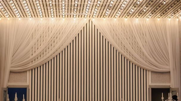 lähikuva valkoinen katto ja osa puheenjohtajiston koristeltu tylli ja valot hääjuhlasalissa - Valokuva, kuva