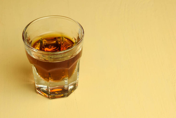 A glass of cognac stands on a beige table. Shot from above - Photo, Image