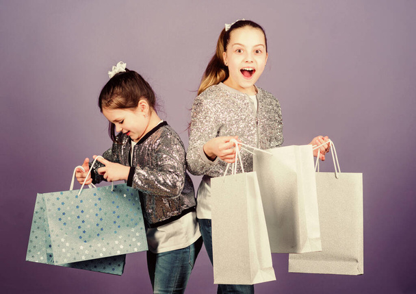 Black friday. Sale and discount. Shopping day. Children bunch packages. Kids fashion. Girls sisters friends with shopping bags violet background. Because image is everything. Shopping and purchase - Foto, imagen