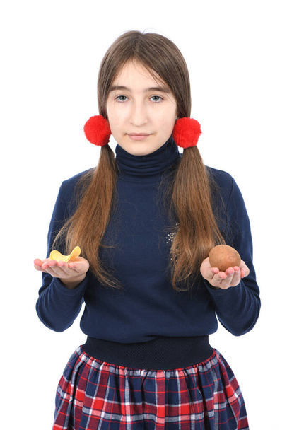 Πορτρέτο του προ-έφηβος κορίτσι ζυγίζει πατάτα και τσιπ. Απομονωμένο σε λευκό φόντο. Φωτογραφία υψηλής ανάλυσης. Πλήρες βάθος πεδίου. - Φωτογραφία, εικόνα