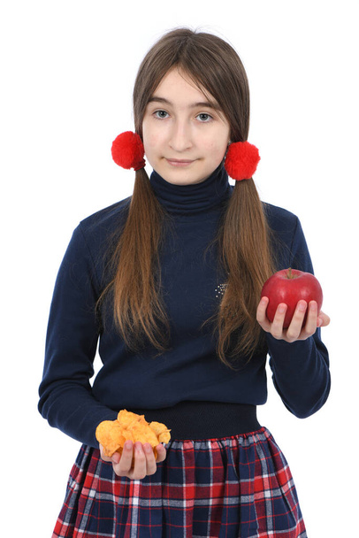Pre-adolescent girl weigh bowls full of potato chips and red apple. Isolated on white background. High resolution photo. Full depth of field.  Concept of choosing healthy and unhealthy food - Photo, Image