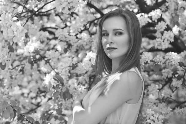 portrait of a young blonde girl in a blue dress. trees in flowers. - Foto, afbeelding