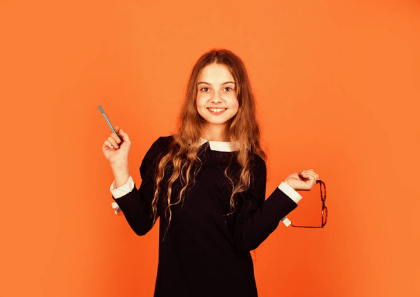 Cute genius. Girl genius brown background. Genius little child hold pen and glasses. School and education. Private teaching. Potential of mind. Creative and genius - Foto, imagen