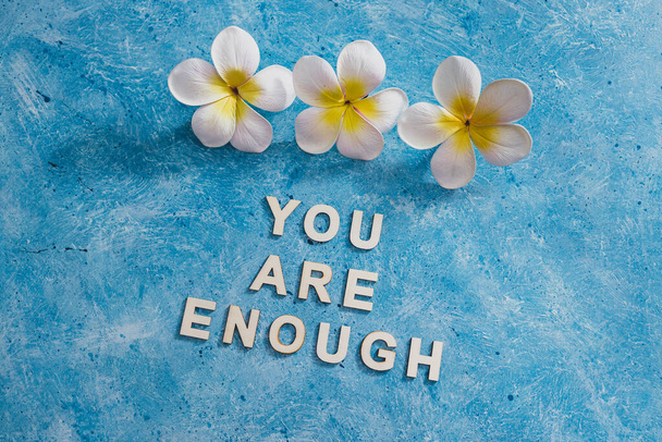 mental health and self-worth concept, You are enouugh text with flowers and blue background - Photo, image