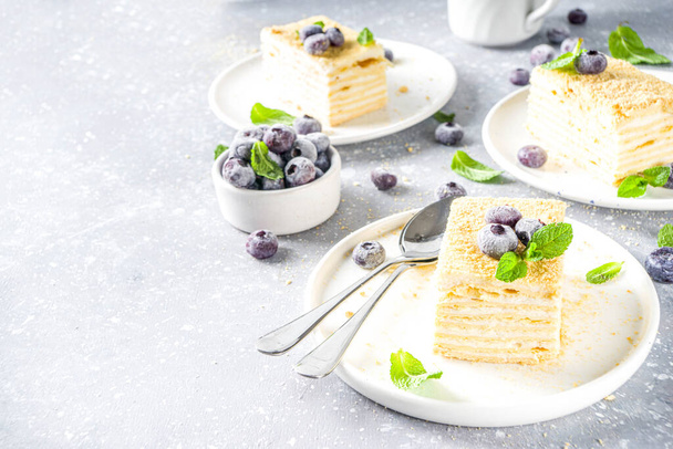 Homemade baked cake Napoleon, Millefeuille. Delicate custard cake garnished with berries and mint. On a gray concrete stone background. - Photo, Image