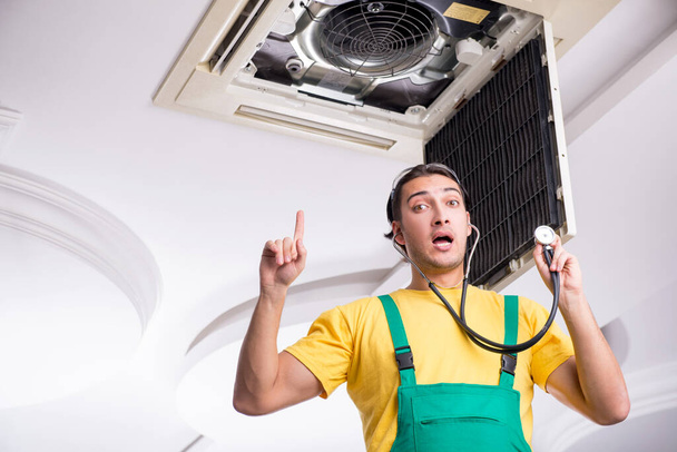 Jovem reparador reparando teto unidade de ar condicionado - Foto, Imagem