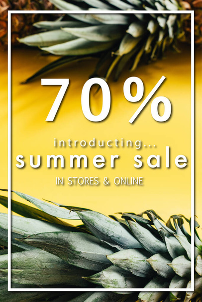 selective focus of green leaves on pineapples on yellow background with summer sale illustration - 写真・画像