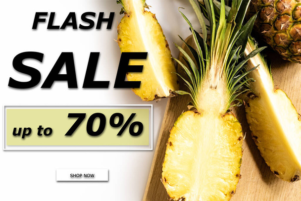bovenaanzicht van gesneden sappige ananas op snijplank op witte achtergrond met flash verkoop illustratie - Foto, afbeelding