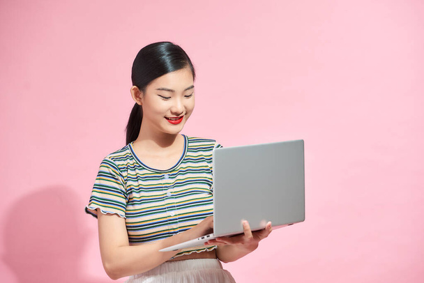 Asian cute young woman smiling standing using laptop computer on hand looking to computer isolated, - Foto, immagini