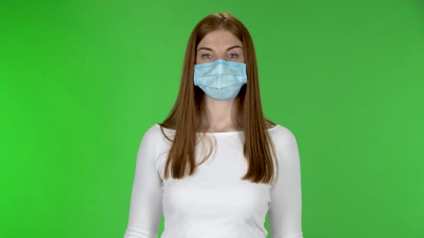 Portrait of young girl in medical protective face mask looking at camera and holding a poster Stop Kovid-19. - Πλάνα, βίντεο