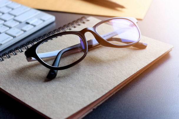 glasses and book on wooden table. film colors tone and soft-focus in the background. over sunlight - Foto, imagen