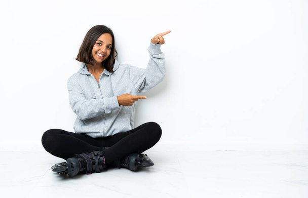 Joven mujer asiática con patines en el suelo apuntando con el dedo hacia un lado y presentando un producto
 - Foto, imagen