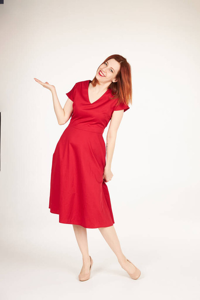 Smiling redhead girl on white background red dress - Foto, imagen