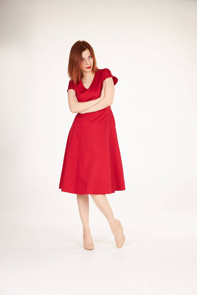 Улыбающаяся рыжая девушка на белом фоне красного платья
 - Фото, изображение