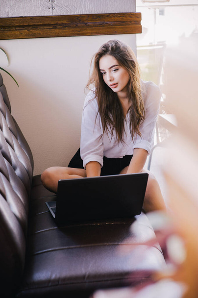 Young beautiful business woman working on a laptop. Beautiful girl in a white shirt at the computer. business woman economist in formal wear concentrated, in front of laptop, stylish, ponder, serious - Фото, изображение
