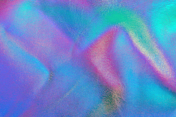 Retro holographic metallic leather background. Abstract colorful vibrant iridescent gradient. Retro futuristic design. Real texture violet, pink, mint and blue colors with scratches and irregularities - Photo, Image