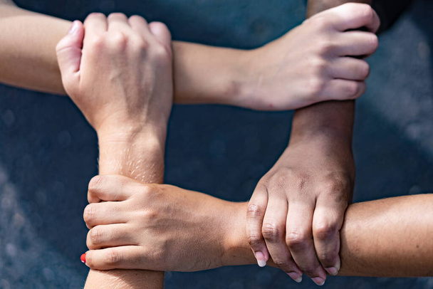 Pessoas multirraciais com mãos negras, latinas, caucasianas e asiáticas segurando um no outro pulso. Unidade e concórdia em equipe multiétnica. Tolerância, trabalho em equipe e conceito anti-racismo. Imagem
 - Foto, Imagem