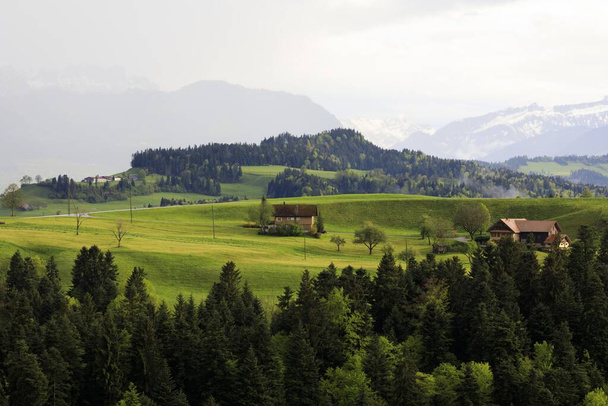 An amazing shot of a rural house in green hills landscape - Foto, afbeelding