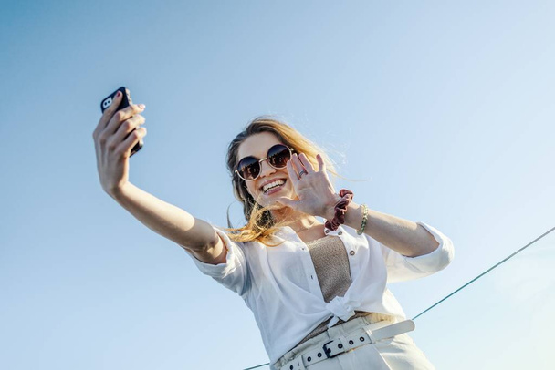 A young stylish woman with sunglasses and white shirt talking a selfie - Φωτογραφία, εικόνα