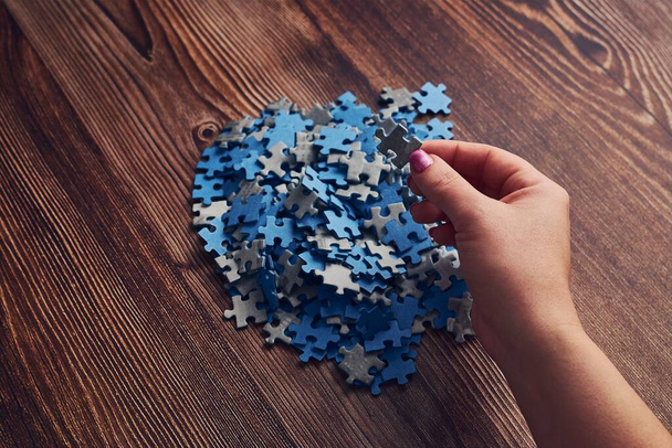 A woman collecting the small pieces of a puzzle - the concept of problem-solving - Φωτογραφία, εικόνα