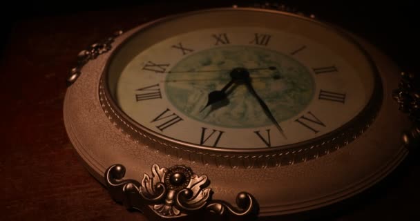 Concepto de tiempo. Gran reloj redondo vintage en mesa de madera con luz abstracta. Ambiente oscuro. Decoración creativa. Enfoque selectivo - Imágenes, Vídeo