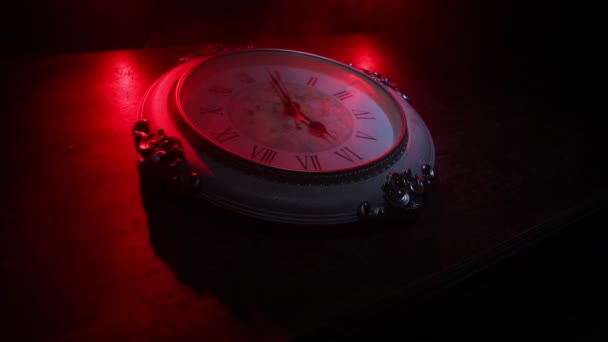 Концепция времени Большие винтажные круглые часы на деревянном столе с абстрактным светом. Темная атмосфера. Творческое оформление. Селективный фокус - Кадры, видео