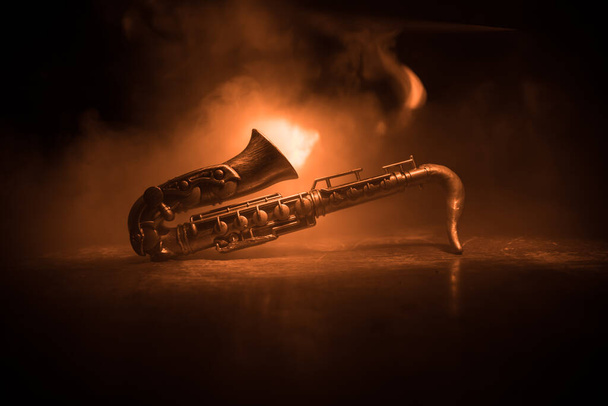 Muziekconcept. Saxofoon jazz instrument. Alto gouden sax miniatuur met kleurrijk getint licht op mistige achtergrond. Saxofoon muziekinstrument bij weinig licht. Selectieve focus - Foto, afbeelding