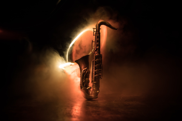 Zenei koncepció. Szaxofon jazz hangszer. Alto arany szaxofon miniatűr színes tónusú fény ködös háttér. Szaxofon hangszer alacsony fényben. Szelektív fókusz - Fotó, kép