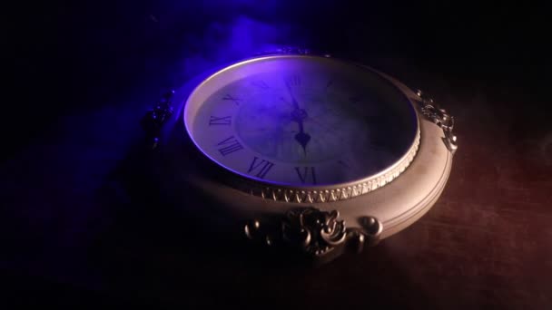 Time concept. Big vintage round clock on wooden table with abstract light. Dark atmosphere. Creative decoration. Selective focus - Footage, Video