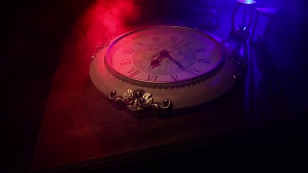 Concepto de tiempo. Gran reloj redondo vintage en mesa de madera con luz abstracta. Ambiente oscuro. Decoración creativa. Enfoque selectivo - Imágenes, Vídeo