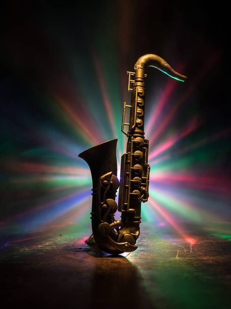 Музична концепція. Саксофонський джазовий інструмент. Альтозолотиста мініатюра з кольоровим тонованим світлом на туманному фоні. Саксофонський музичний інструмент в малому світлі. Вибіркове зосередження - Фото, зображення