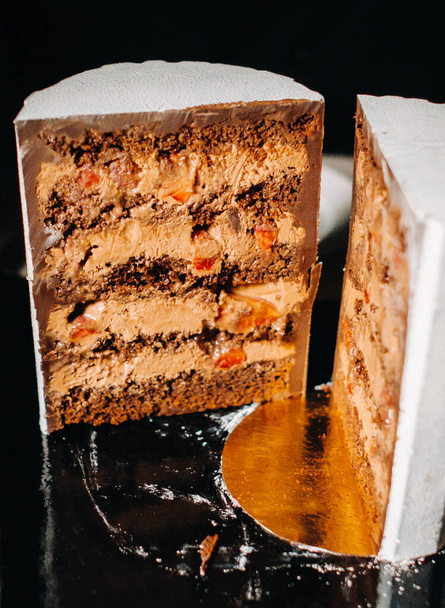 Amazing Cakes. Sliced chocolate wedding cake cake with amazing filling on a black background.Large cake in white chocolate. - Фото, изображение
