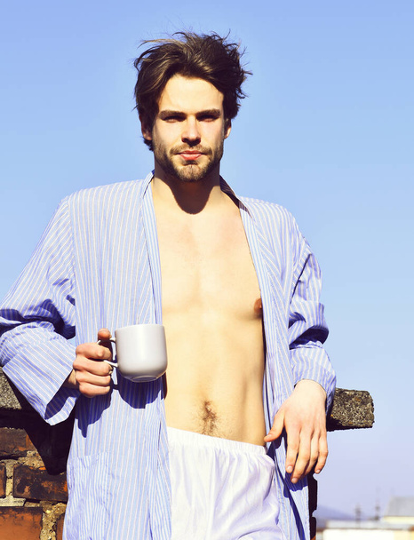 Caucasian macho in blue striped pajamas holding cup - Photo, Image