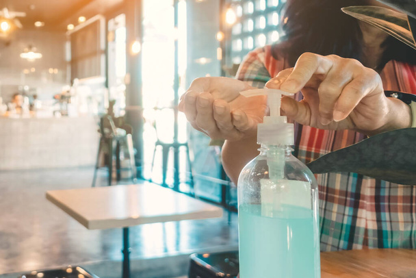 手掃除用ブルーアルコールジェルボトルはコロナウイルス(Covid-19)の拡散を防ぐために、カフェに顧客のための入り口サービスを配置します。医療の概念. - 写真・画像