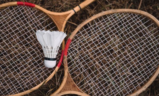 Wooden badminton rackets and a white feather shuttlecock. The game of badminton. Hobbies and outdoor recreation. - 写真・画像