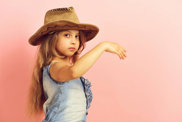 Kid with serious face and long hair wears jeans dress - 写真・画像