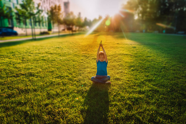 lapsi harjoittaa joogaa auringonlaskun aikaan, lapsi liikunta luonnossa - Valokuva, kuva