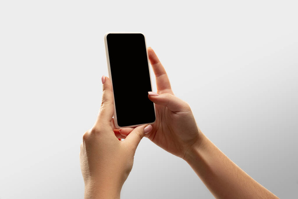 Close up female hands holding smartphone with blank screen during online watching of popular sport matches and championships all around the world. Copyspace for ad - Photo, image